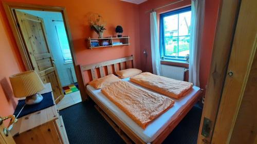a bedroom with a bed with orange walls and a window at Lindow Rügen in Putbus