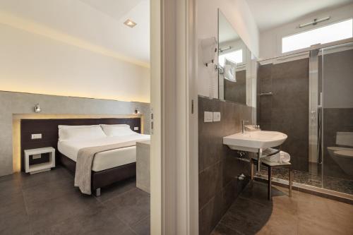 Baldinini Hotel في ريميني: غرفة نوم بسرير وحمام مع حوض