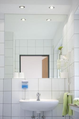 a white bathroom with a sink and a mirror at Hotel Emmerich in Winningen