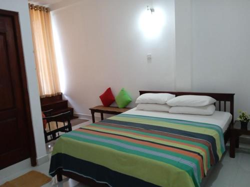 1 dormitorio con 1 cama con una manta a rayas de colores en Alex Home Stay, en Kandy