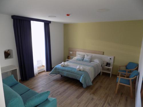 1 dormitorio con 1 cama y 1 sofá azul en Hotel Rural SUEÑOS DEL QUIJOTE en Madridejos