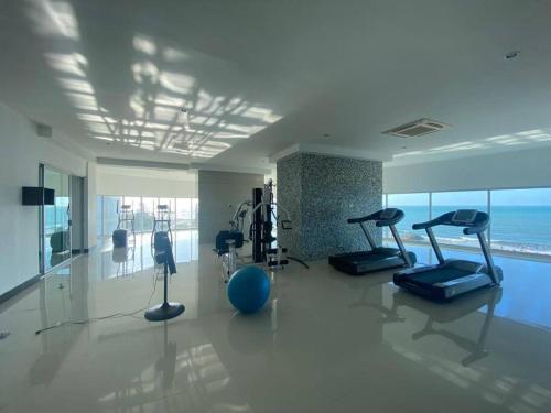 a gym with cardio equipment in a large room with the ocean at Apartamento frente a la playa in Cartagena de Indias