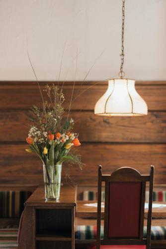 a vase of flowers on a table with a lamp at Hotel Bären in Feldkirch