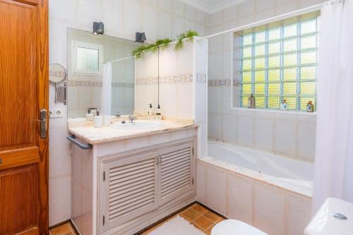 uma casa de banho com um lavatório, uma banheira e um espelho. em Casa Arturo em Sa Coma