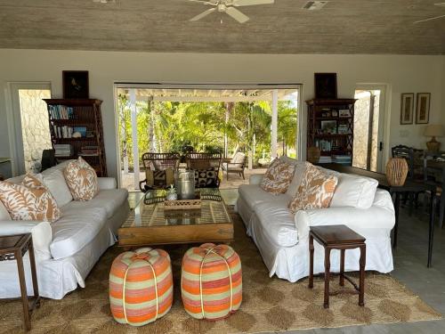 una sala de estar con sofás blancos y una mesa. en Twin Coves House home en Governor's Harbour