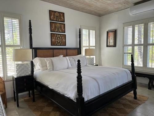 a bedroom with a large bed in a room with windows at Twin Coves House home in Governorʼs Harbour