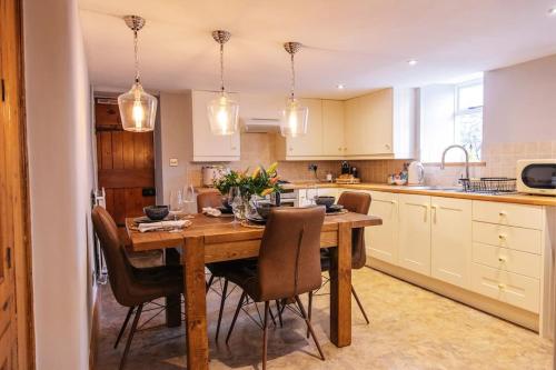 a kitchen with a wooden table and chairs at Ava Lily Cottage, Tideswell in Tideswell