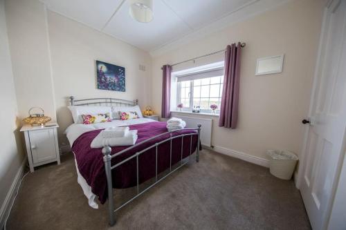 a bedroom with a bed with purple sheets and a window at Cliff Stud Retreat, Helmsley, Frankel Cottage in Helmsley