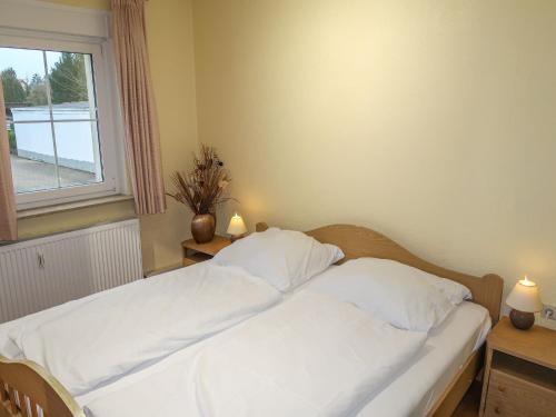 una camera da letto con un letto con lenzuola bianche e una finestra di Apartment Nordlicht by Interhome a Bremerhaven