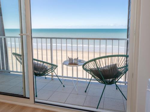 a balcony with two chairs and a table on the beach at Apartment Les Mouettes by Interhome in Jullouville-les-Pins
