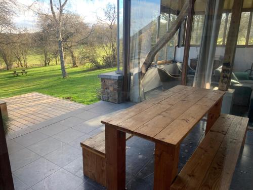 a wooden bench on a patio with a view of a park at Gîte Banet-Sart à Daverdisse in Daverdisse