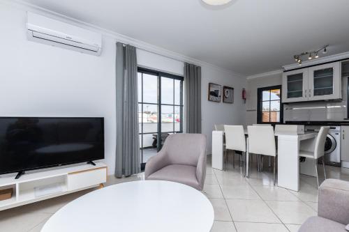 a living room with a television and a table and chairs at Golden Maré BY ALGARVEMANTA in Manta Rota