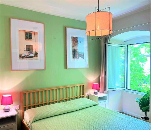 a bedroom with a bed with green walls and a window at Al Glicine Apartments in Lazise
