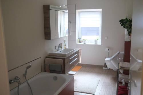 een badkamer met een bad, een wastafel en een raam bij Ferienwohnung Arendsee in Arendsee