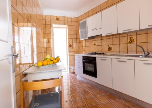 a kitchen with white cabinets and a bowl of fruit on a counter at Lucia Maison in Ischia