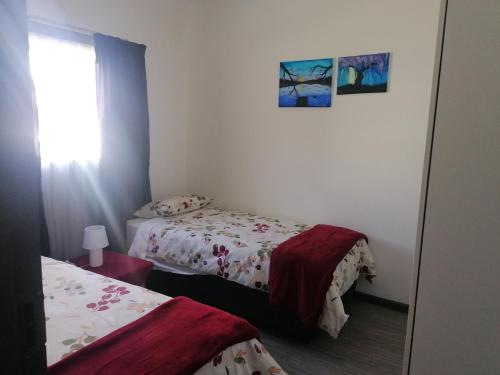 Habitación pequeña con 2 camas y ventana en Kosies Nest Gastehuis, en Ciudad del Cabo