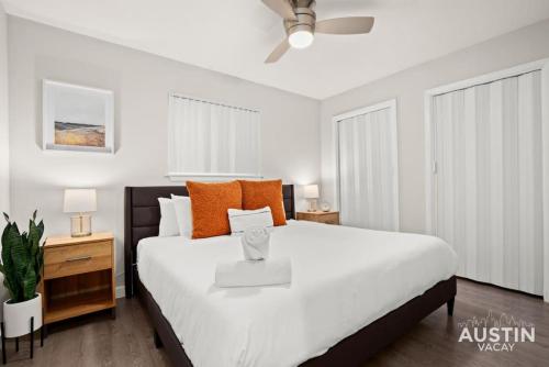ein Schlafzimmer mit einem großen weißen Bett mit orangefarbenen Kissen in der Unterkunft Fun Weekend Getaway Modern Decor, Parking, and Deck in Austin
