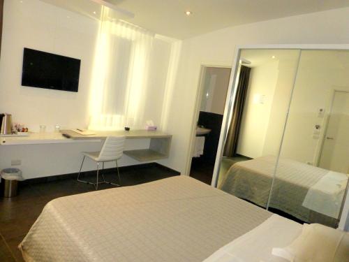 a bedroom with a bed and a desk and a mirror at Baldinini Hotel in Rimini