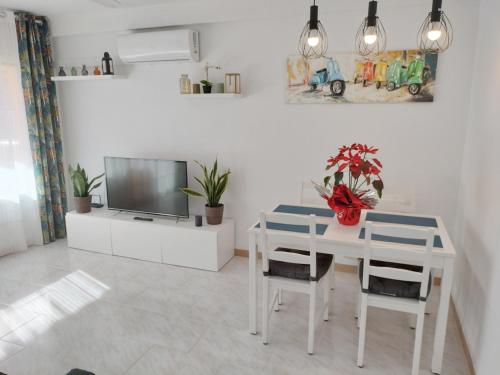 een witte eetkamer met een witte tafel en een tv bij CAMBRILS BEACH APARTMENT in Cambrils