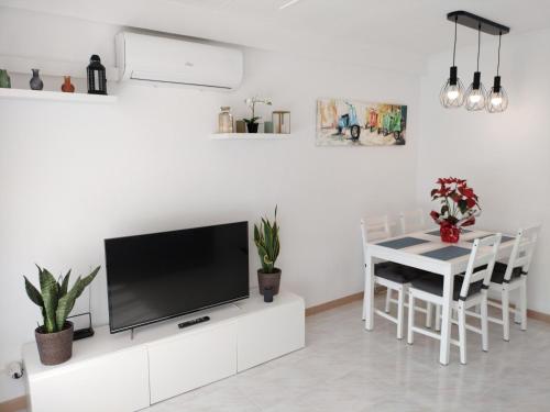 a living room with a tv and a table with chairs at CAMBRILS BEACH APARTMENT in Cambrils