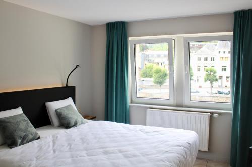 een slaapkamer met een bed en 2 ramen bij Hotel LA PLAGE in Bouillon