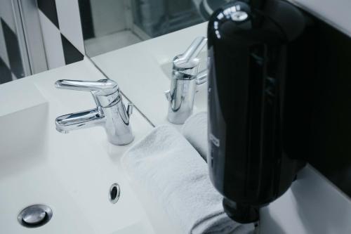 a black soap dispenser sitting on a bathroom sink at LOVE ROOM ou pas ! Chamalières in Chamalières