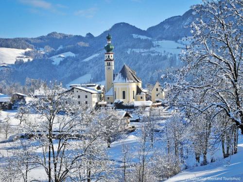 a church with a clock tower in the snow at Apartment Theresia by Interhome in Alpbach