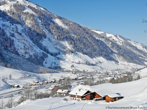 a small village in the snow in front of a mountain at Apartment Ingrid by Interhome in Fusch an der Glocknerstraße