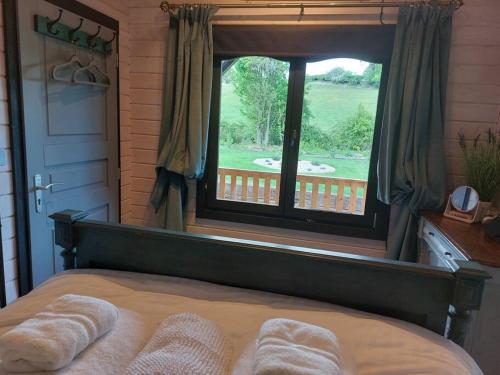 a bedroom with a large window with towels on a bed at The Malvern Hills, Courtyard Cabins,Tom Cabin in Great Malvern