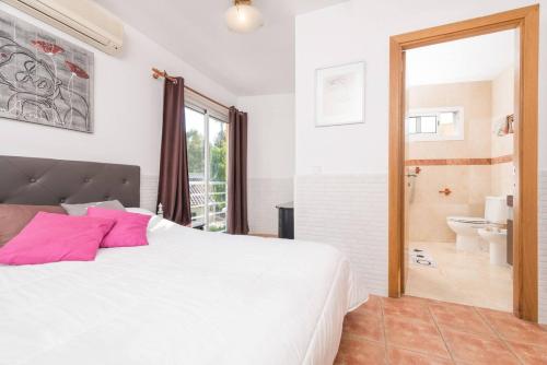 um quarto com uma grande cama branca e uma casa de banho em 3 bedrooms house with private pool and enclosed garden at Puerto de Alcudia 1 km away from the beach em Port d'Alcudia