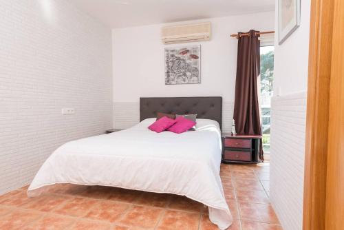 um quarto com uma cama branca e almofadas cor-de-rosa em 3 bedrooms house with private pool and enclosed garden at Puerto de Alcudia 1 km away from the beach em Port d'Alcudia