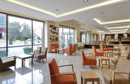 um restaurante com cadeiras e mesas cor de laranja e janelas em ibis Amman em Amã