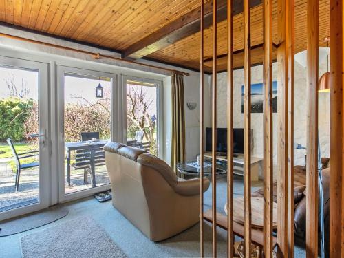 a living room with a chair and a table and sliding glass doors at Apartment Nordsee-Ferienhaus-2 by Interhome in Friedrichskoog