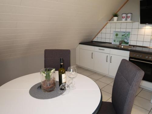 a kitchen with a white table with wine bottles and chairs at Apartment Rosenboom by Interhome in Wiarden