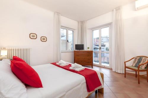 Un dormitorio con una cama con almohadas rojas y una silla en [500 mt. DAL MARE] WiFi Clima & Design en Porto San Giorgio