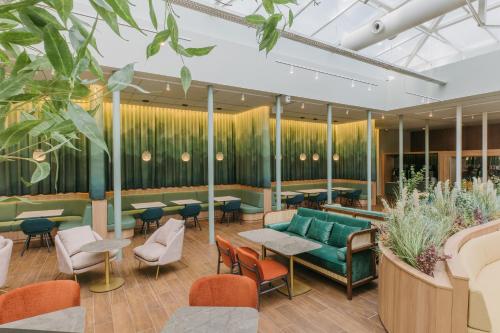 a lobby with tables and chairs and plants at Catalonia Barcelona Plaza in Barcelona