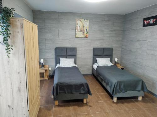 two twin beds in a room with a wall at Hotel Apartamenty 72 in Płock