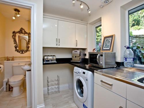 a kitchen with white cabinets and a washer and dryer at Bishopsgate in Torquay