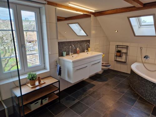 a bathroom with a sink and a tub and windows at Ferienhaus Kluser in Oberriet