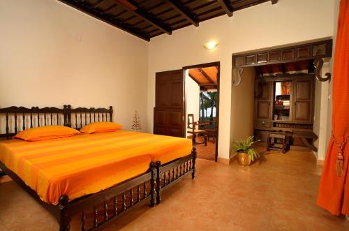 a bedroom with a bed with an orange blanket at Vembanad House Boutique Back Water Retreat in Alleppey