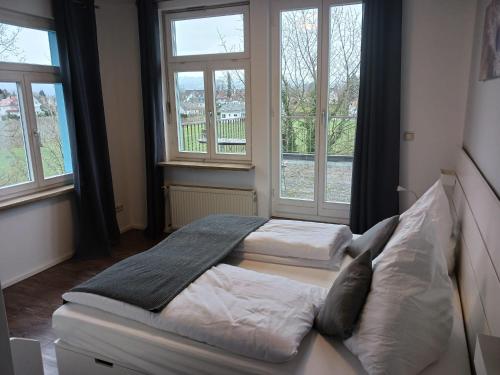 two beds in a room with two windows at Gasthaus Wilhelmshöhe in Wasserburg am Bodensee