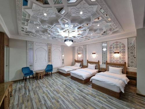 a room with four beds and two blue chairs at Latifa Begim Boutique Hotel in Bukhara