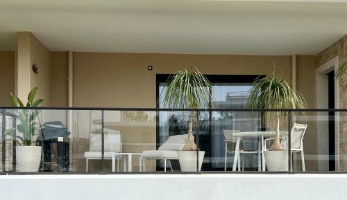 d'un balcon avec des plantes en pot, une table et des chaises. dans l'établissement L'apart'83 - T2 classé 5 étoiles - Belle vue sur la baie du Lazaret, à Saint-Elme