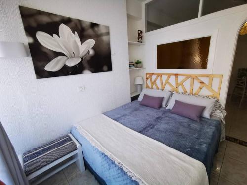 1 dormitorio con 1 cama y una pintura en la pared en Estudio Ana, en Puerto de la Cruz
