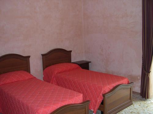 two beds in a small room with red sheets at Aia di Lazzaro Agriturismo in Casalbore