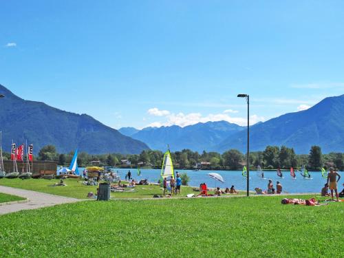 a group of people sitting on the grass near a lake at Apartment Azalea - GLA103 by Interhome in Gera Lario