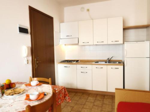 eine Küche mit weißen Schränken und einem Tisch mit Essen drauf in der Unterkunft Apartment Pleione-1 by Interhome in Bibione