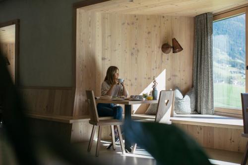 a woman sitting at a table in a room at Bühelwirt in San Giacomo