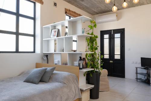 1 dormitorio con cama y estanterías blancas en Roam Gozo - Studio Hamrija - Modern Cozy Tiny Home Set In Gozo's Oldest Village, en Xewkija