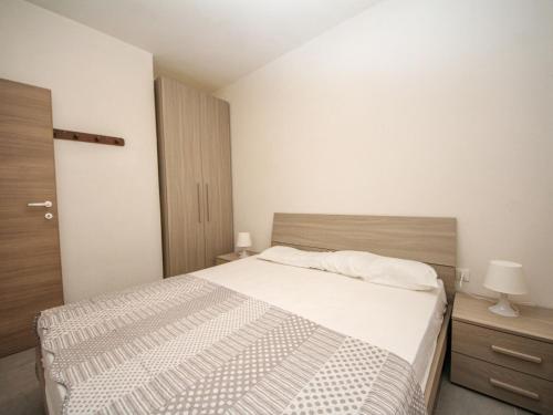 een kleine slaapkamer met een bed, een nachtkastje en een deur bij Apartment Villa Fausta by Interhome in Rosolina Mare